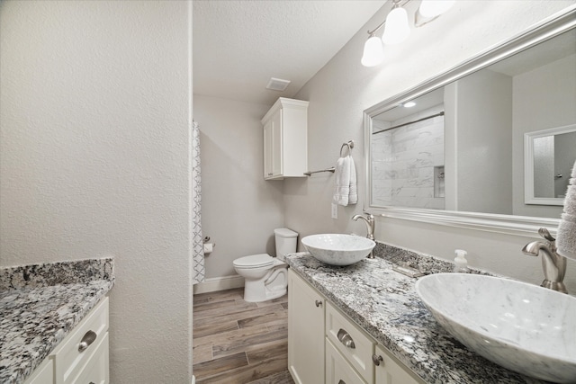 bathroom featuring a textured ceiling, hardwood / wood-style flooring, vanity, and toilet