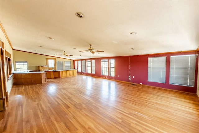 unfurnished living room with a healthy amount of sunlight, ceiling fan, light hardwood / wood-style floors, and crown molding