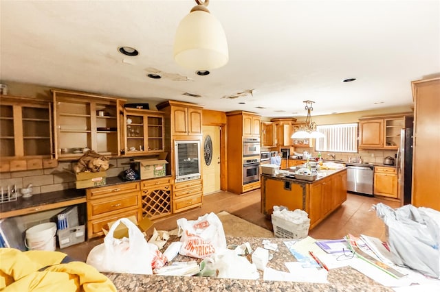 kitchen featuring a kitchen island, tasteful backsplash, pendant lighting, appliances with stainless steel finishes, and wine cooler