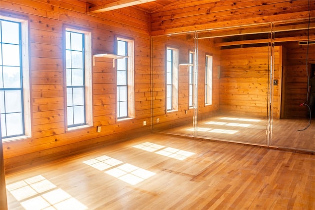 unfurnished room with plenty of natural light, light hardwood / wood-style floors, and wooden walls