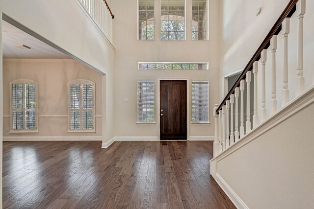 foyer featuring dark wood-type flooring, crown molding, and a towering ceiling