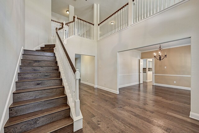 staircase featuring a notable chandelier, hardwood / wood-style floors, and a high ceiling