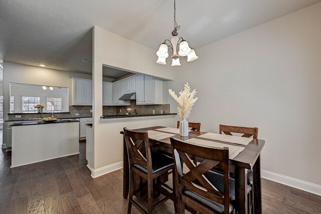 dining area with an inviting chandelier and dark hardwood / wood-style flooring