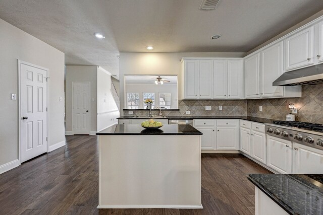 kitchen with appliances with stainless steel finishes, sink, dark hardwood / wood-style flooring, white cabinetry, and dark stone countertops