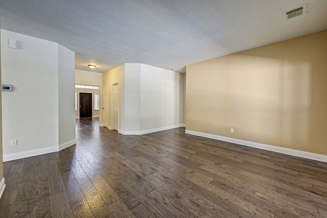 spare room featuring a textured ceiling and dark hardwood / wood-style flooring