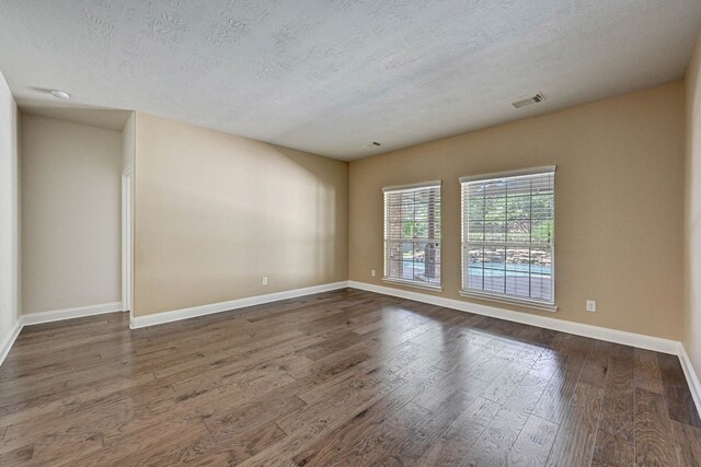 spare room with dark wood-type flooring and a textured ceiling