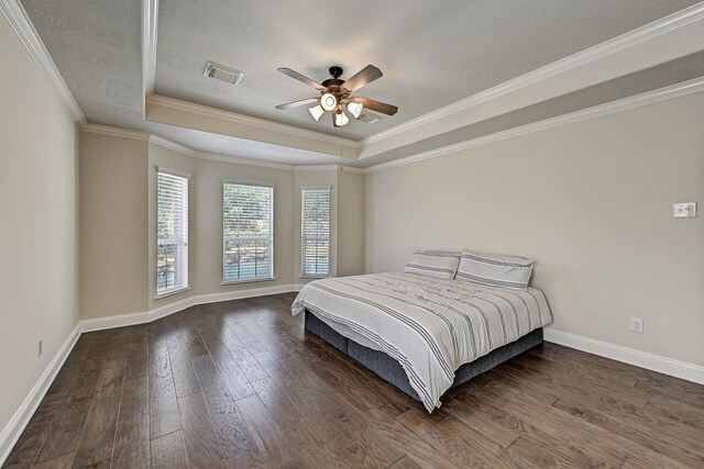 bedroom with crown molding, a raised ceiling, dark hardwood / wood-style floors, and ceiling fan