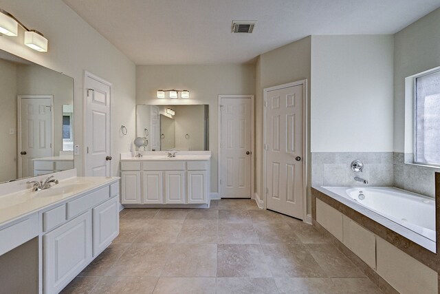 bathroom with vanity, tiled bath, and tile patterned flooring