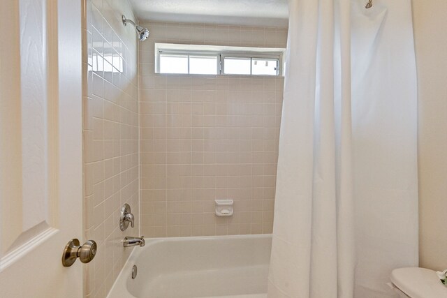 bathroom featuring toilet and shower / bath combo with shower curtain