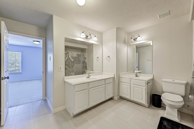 bathroom with vanity, toilet, a textured ceiling, and tile patterned flooring