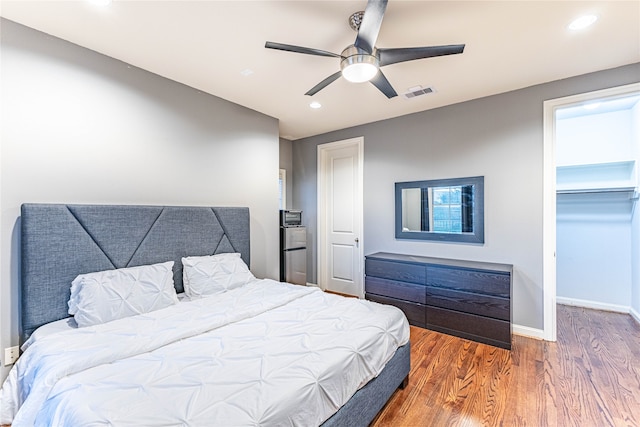 bedroom with a closet, dark hardwood / wood-style floors, a spacious closet, and ceiling fan