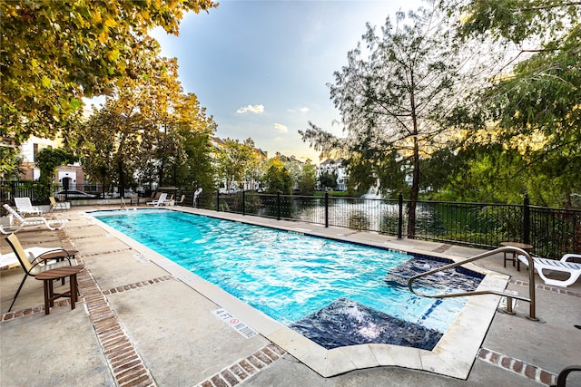 view of pool featuring a water view and a patio