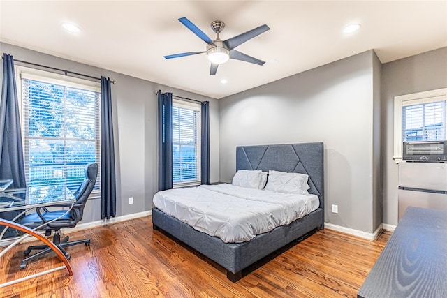 bedroom featuring multiple windows, ceiling fan, cooling unit, and hardwood / wood-style flooring