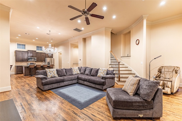 living room with ceiling fan with notable chandelier, light wood-type flooring, and ornamental molding