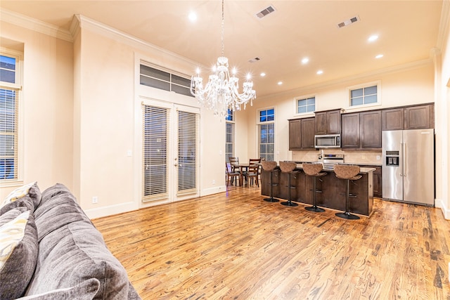 kitchen with a breakfast bar, appliances with stainless steel finishes, light hardwood / wood-style floors, and an island with sink