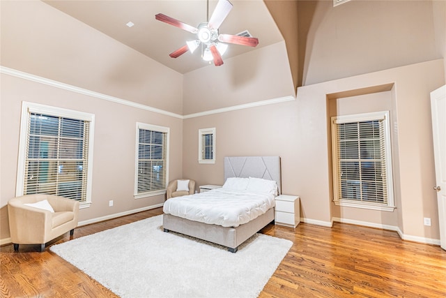 bedroom with hardwood / wood-style floors, high vaulted ceiling, and ceiling fan