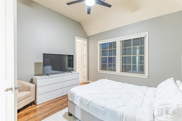 bedroom with ceiling fan, vaulted ceiling, and light wood-type flooring