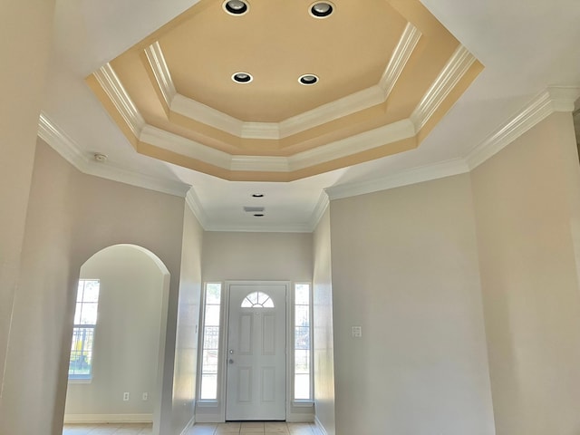 tiled foyer featuring crown molding, a wealth of natural light, and a raised ceiling