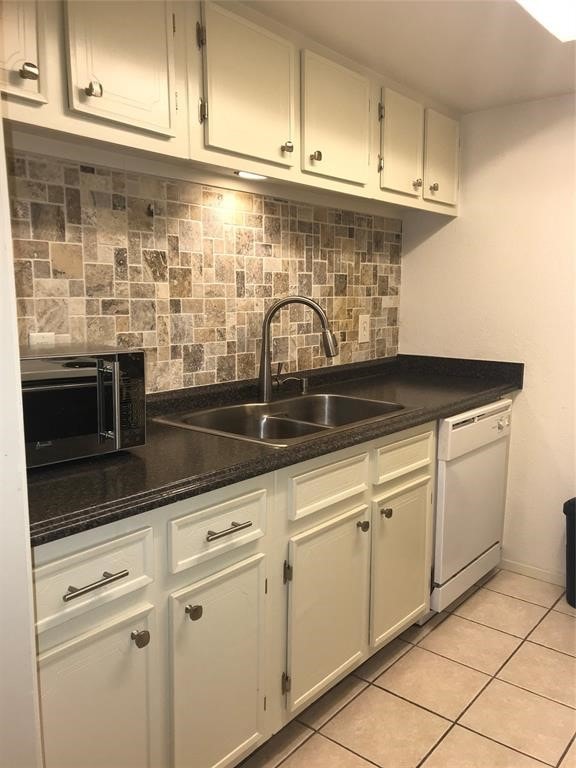 kitchen featuring light tile patterned floors, sink, tasteful backsplash, white cabinetry, and dishwasher