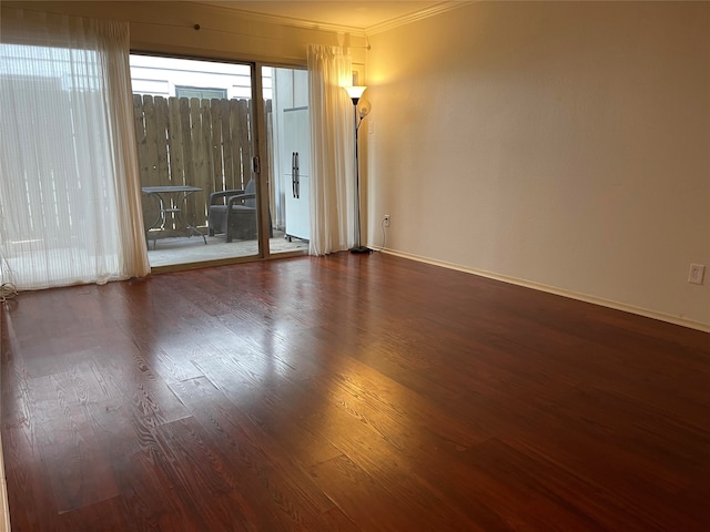 empty room featuring ornamental molding and dark wood-type flooring