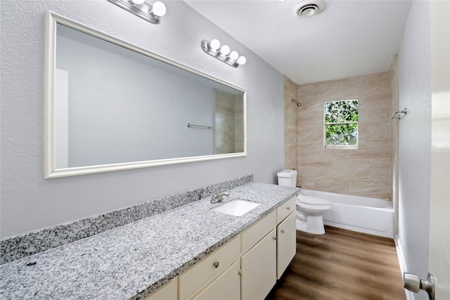 full bathroom featuring tiled shower / bath, hardwood / wood-style floors, vanity, and toilet