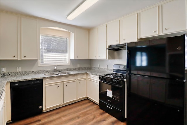 kitchen with white cabinetry, sink, black appliances, and light hardwood / wood-style flooring