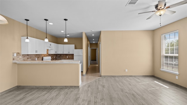 kitchen featuring white cabinets, kitchen peninsula, white appliances, tasteful backsplash, and light hardwood / wood-style flooring