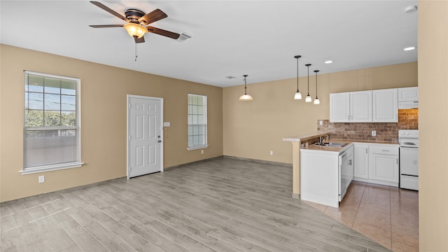 kitchen featuring white appliances, kitchen peninsula, white cabinets, and light wood-type flooring