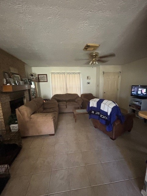 living room with tile patterned flooring, ceiling fan, and a textured ceiling