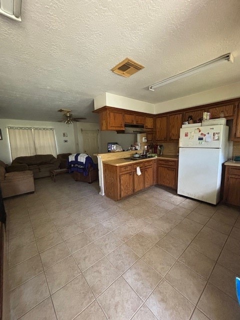 kitchen with ceiling fan, white refrigerator, light tile patterned floors, and a textured ceiling