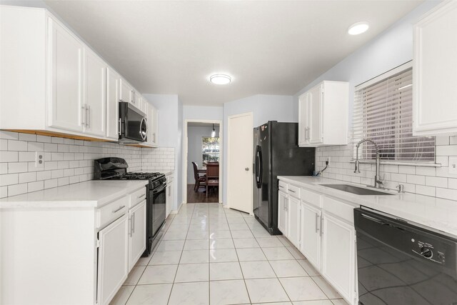 kitchen featuring tasteful backsplash, sink, white cabinets, light tile patterned floors, and black appliances