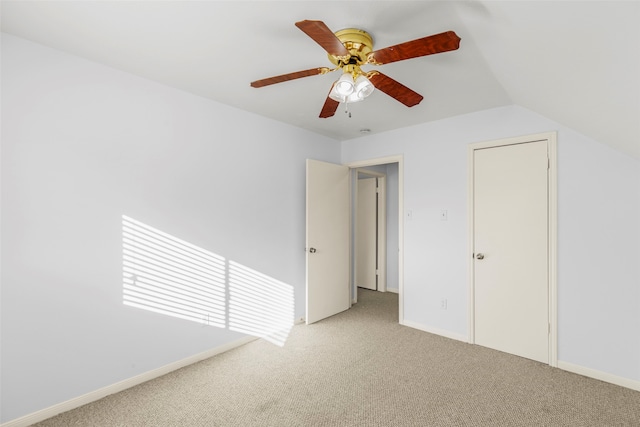 unfurnished bedroom featuring ceiling fan, a closet, light carpet, and lofted ceiling