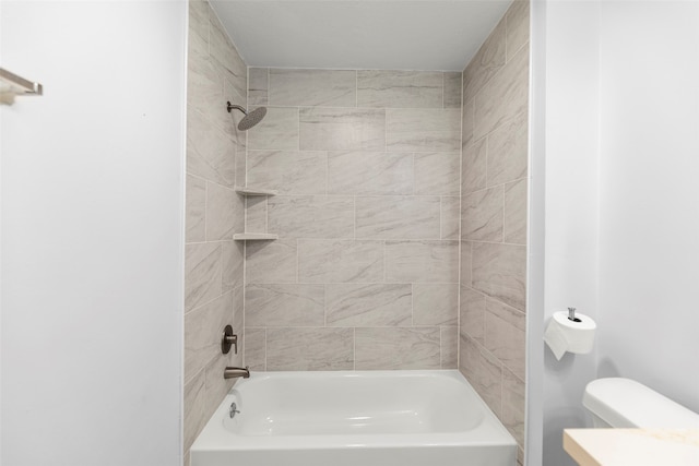 bathroom with toilet and tiled shower / bath