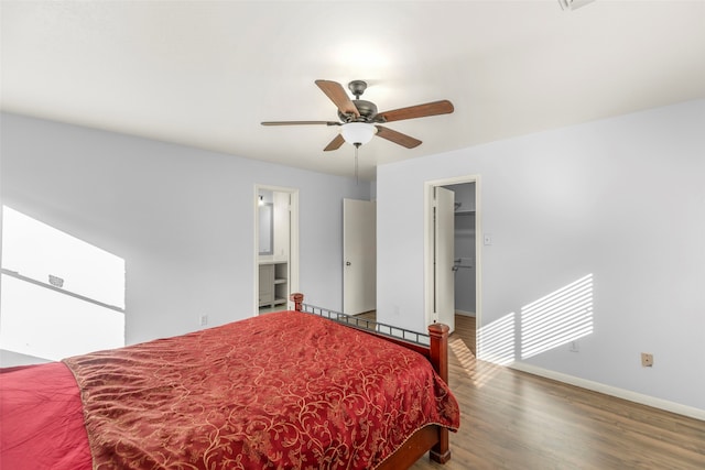 bedroom featuring ceiling fan, a walk in closet, wood-type flooring, and ensuite bath