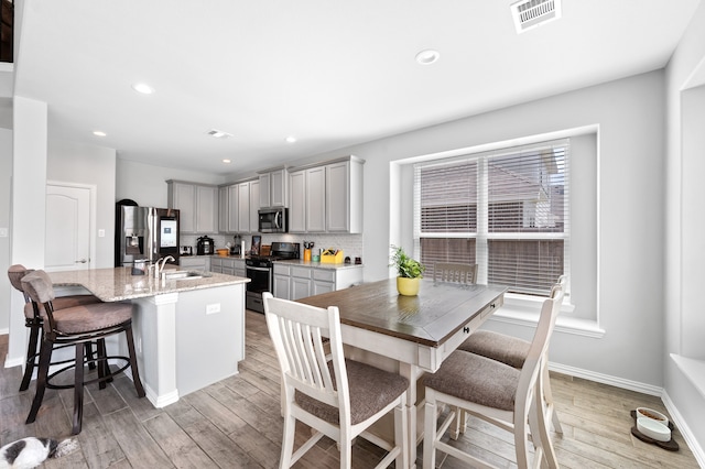 kitchen with light wood-type flooring, appliances with stainless steel finishes, sink, and gray cabinetry