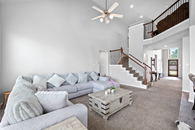 carpeted living room with ceiling fan and a towering ceiling