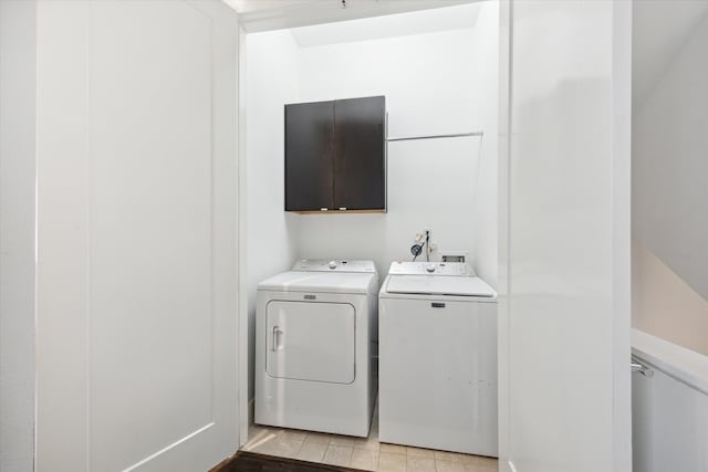 clothes washing area featuring cabinets and separate washer and dryer