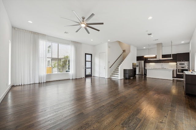 unfurnished living room featuring dark wood-type flooring, ceiling fan, and sink