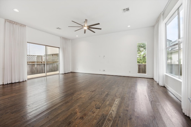 unfurnished room featuring ceiling fan, a healthy amount of sunlight, and dark hardwood / wood-style floors