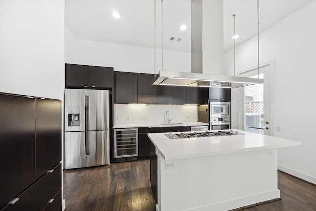 kitchen featuring dark hardwood / wood-style flooring, appliances with stainless steel finishes, a center island, and beverage cooler