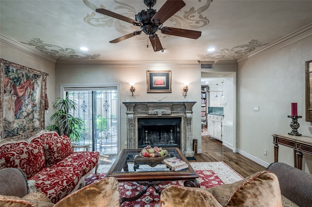 living room with a high end fireplace, visible vents, baseboards, ornamental molding, and wood finished floors