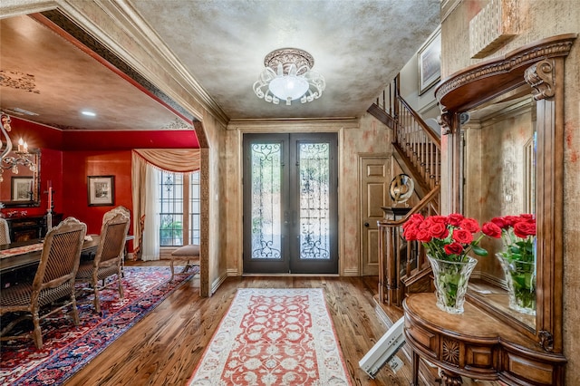 entryway with stairs, an inviting chandelier, wood finished floors, and french doors