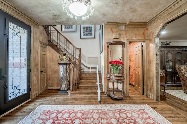 entrance foyer featuring stairs, wood-type flooring, and ornamental molding