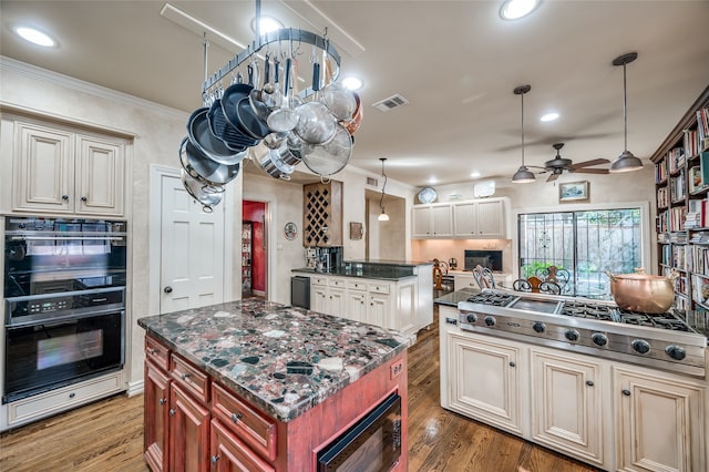 kitchen with cream cabinetry, black appliances, hardwood / wood-style flooring, and a center island