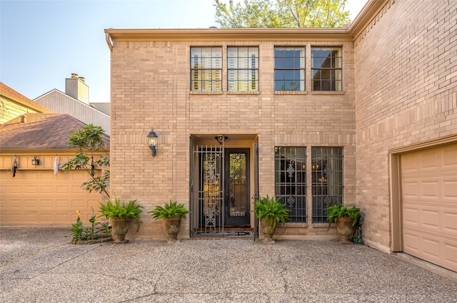 view of exterior entry with a garage and brick siding