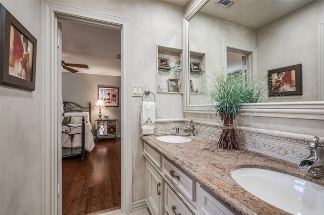 bathroom featuring a sink, a ceiling fan, wood finished floors, and double vanity