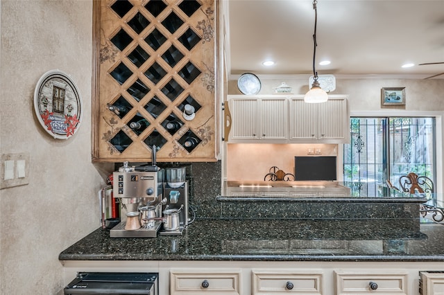 kitchen featuring decorative backsplash, cream cabinetry, ornamental molding, and dark stone counters