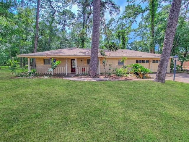 ranch-style house featuring a garage, a front lawn, and covered porch