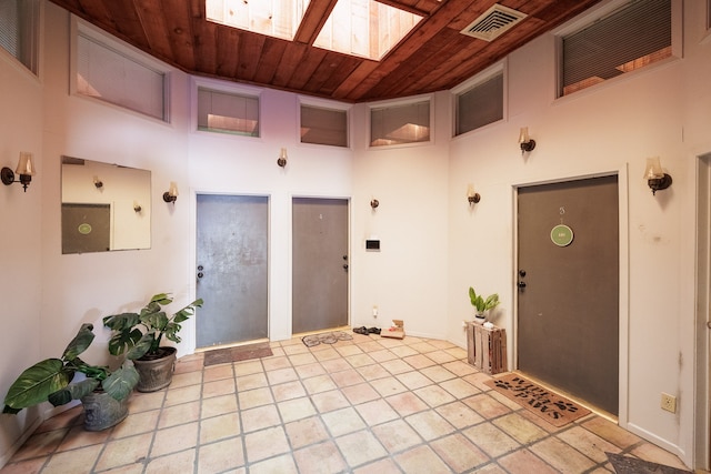 interior space featuring a towering ceiling, wood ceiling, and a skylight