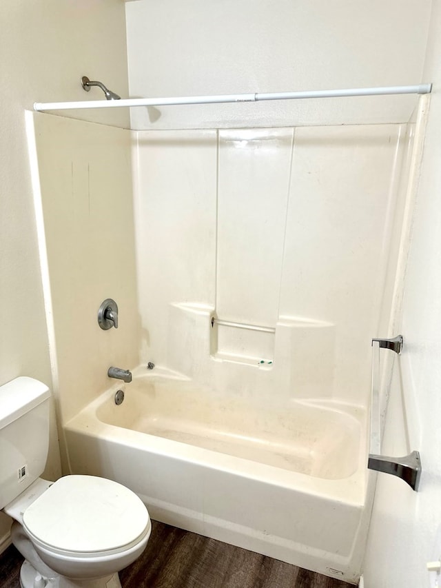 bathroom with washtub / shower combination, hardwood / wood-style flooring, and toilet